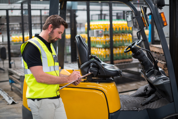 Factory worker with clipboard assessing equipment for clearance